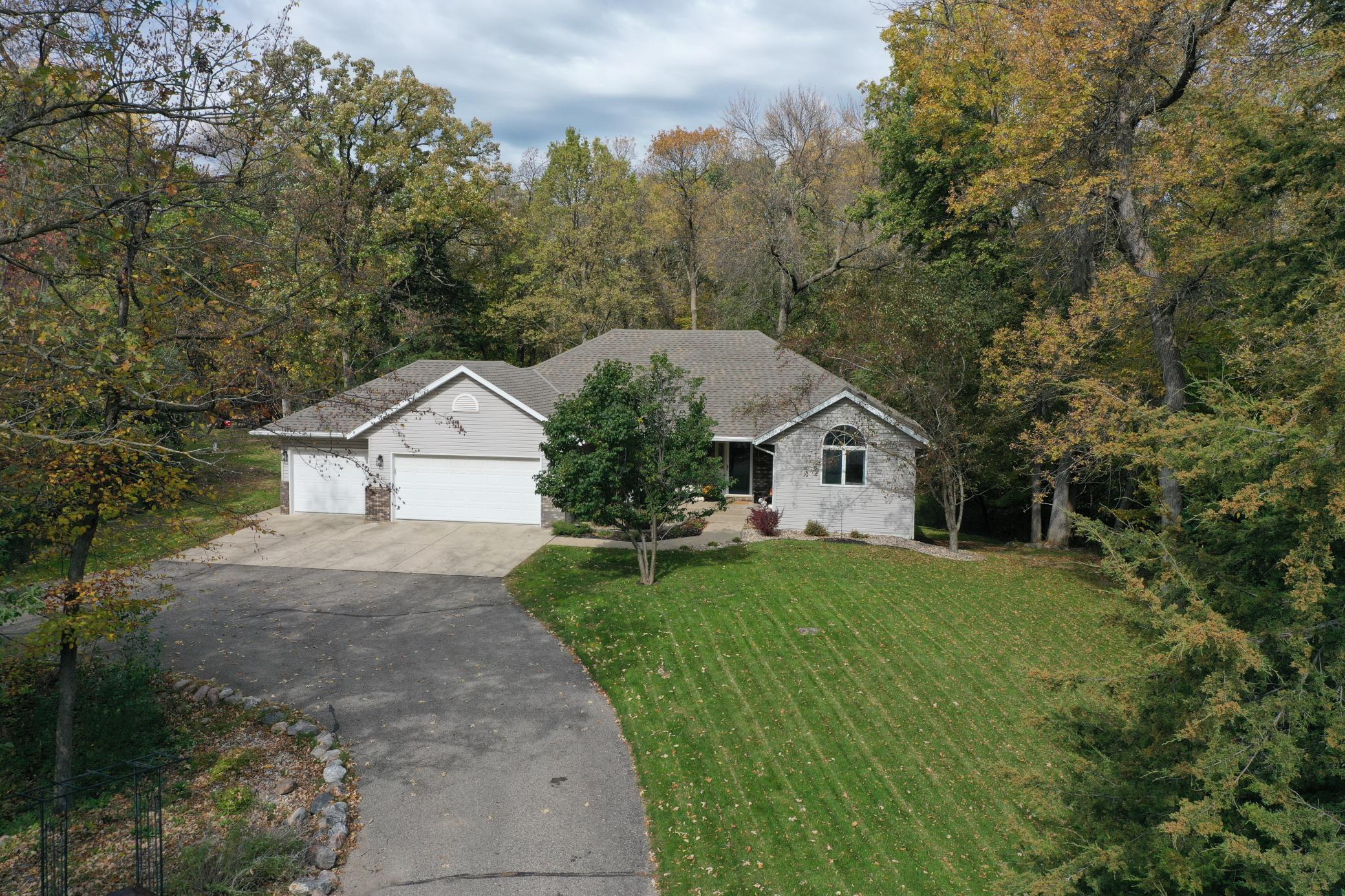 Single-story home with an attached garage, curved driveway, and mature trees.