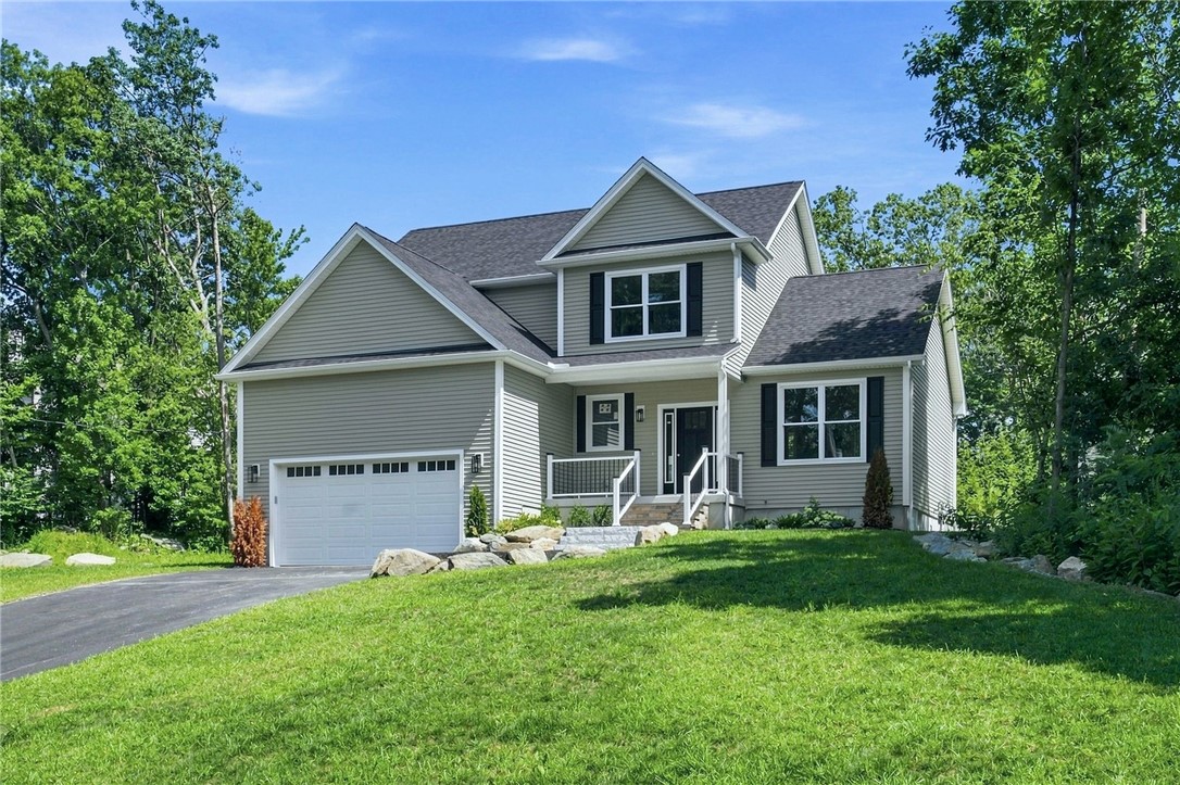 Gray two-story house with a two-car garage, front porch, and broad green lawn.