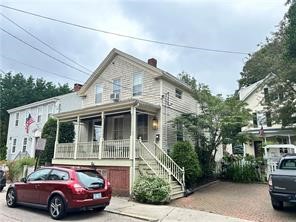 Two-story house with a covered porch and exterior staircase, viewed from the street.