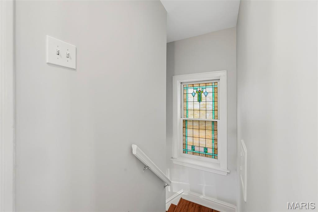 Stairwell with a colorful stained-glass window above wooden steps.
