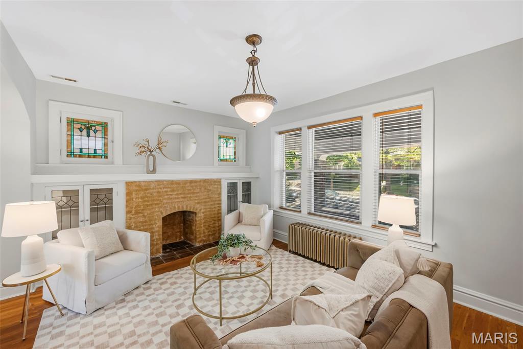 Living room with a brick fireplace, stained-glass windows, and seating around a glass coffee table.