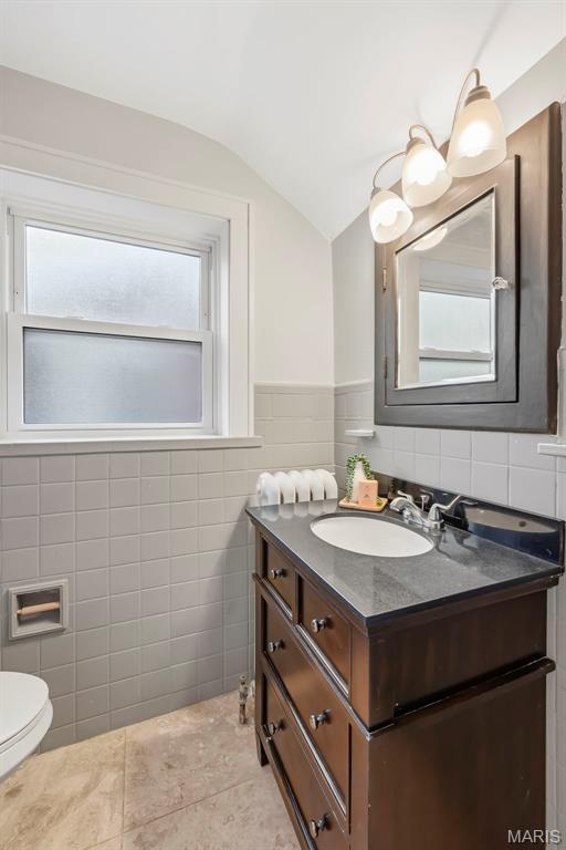 Bathroom with a dark wood vanity, gray countertop, oval sink, and frosted-glass window.