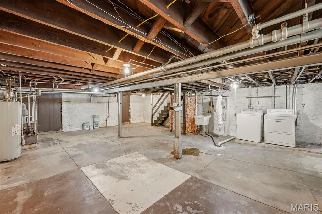 Unfinished basement with exposed beams, concrete floor, and washer and dryer.
