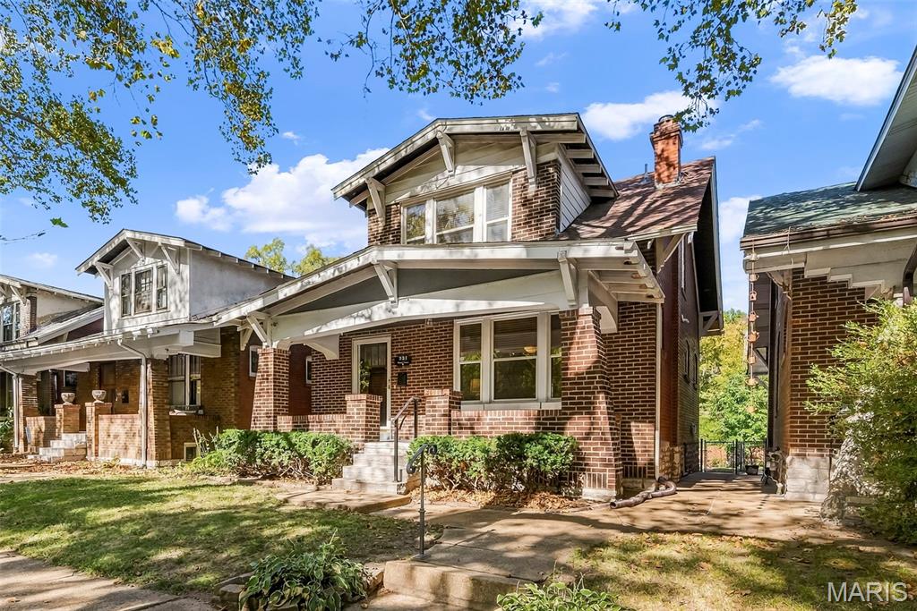 Red brick house with a broad covered porch, white trim, and an upper dormer.
