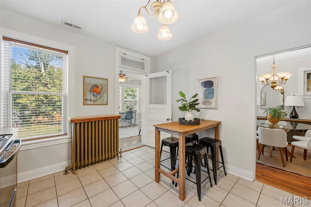 Kitchen with a wooden island table, black stools, and a vintage radiator beneath the window.
