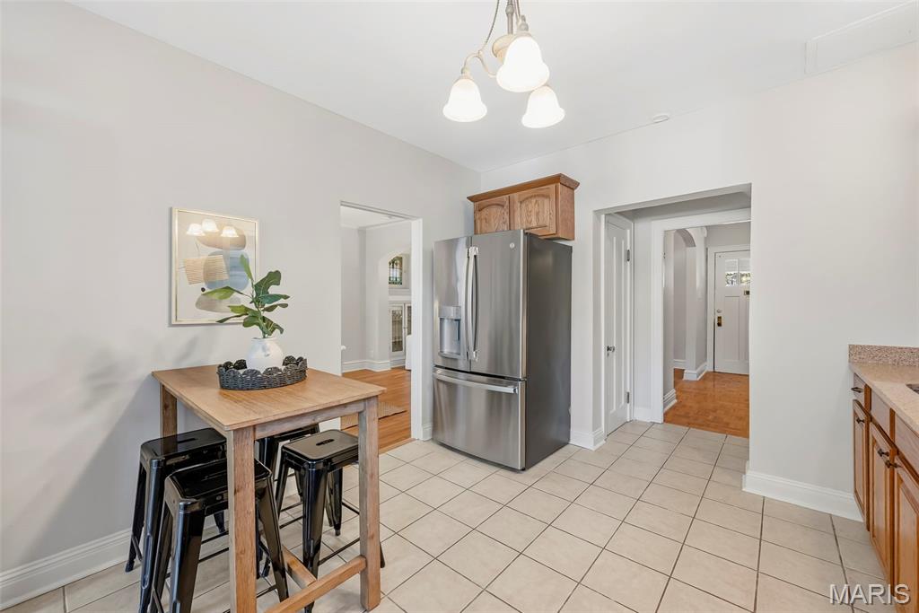 Kitchen with a stainless-steel refrigerator, tiled floor, and small wooden dining table.