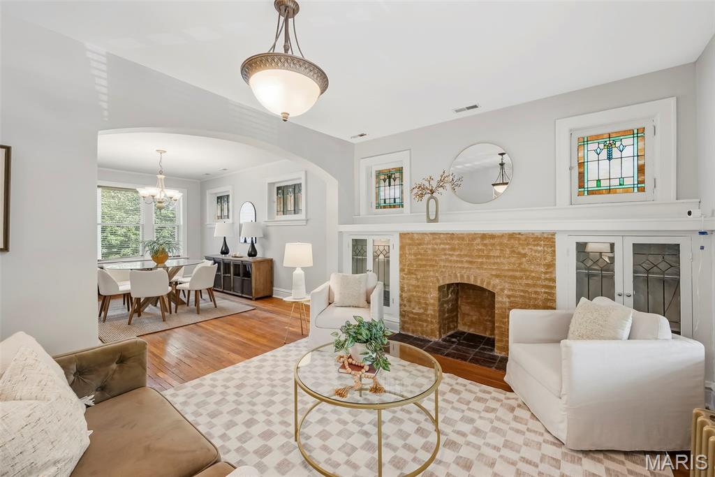 Living room with a brick fireplace, stained-glass windows, and an adjoining dining area.