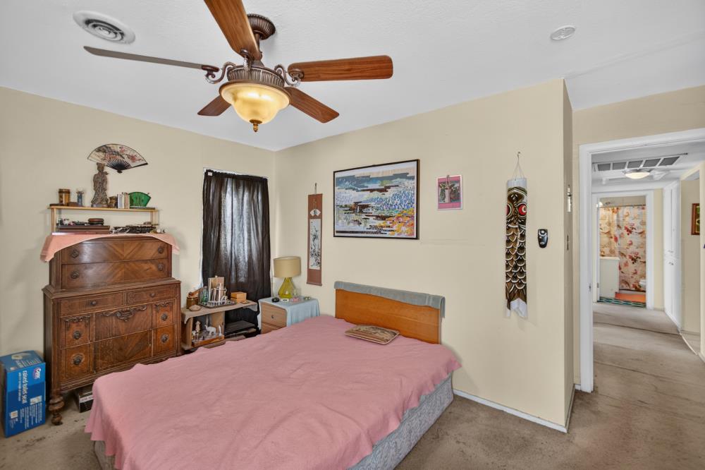 Bedroom with a pink bedspread, ceiling fan, and large wooden dresser.