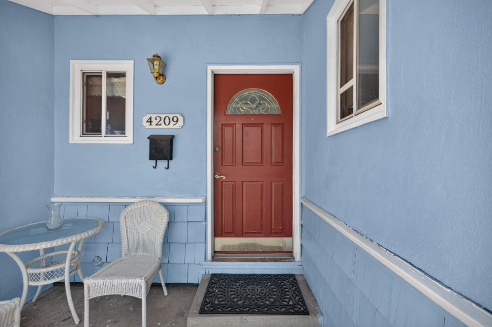 Home’s front porch with a red entry door, blue walls, and wicker seating.