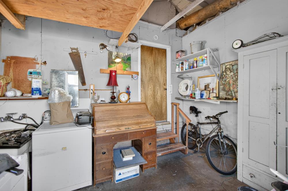 Garage workshop with a wooden workbench, laundry appliances, bicycles, and exposed ceiling framing.
