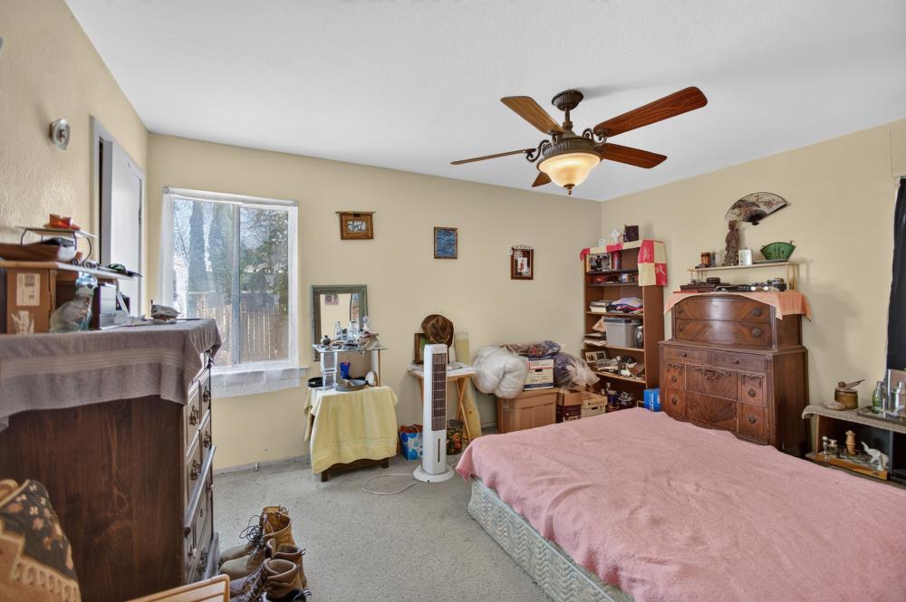 Bedroom with a pink-covered bed, wooden furniture, and a ceiling fan.