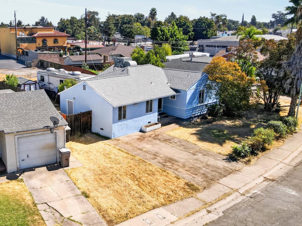 Blue single-story house with a broad concrete driveway and dry front yard, viewed from above.