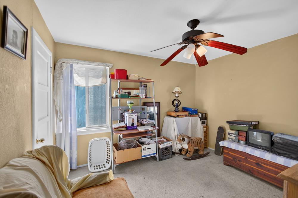 Furnished room with a ceiling fan, window, sofa, television, and rocking horse.