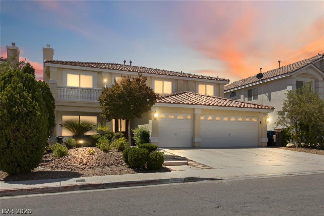 Two-story stucco home with a three-car garage and landscaped front yard at sunset.