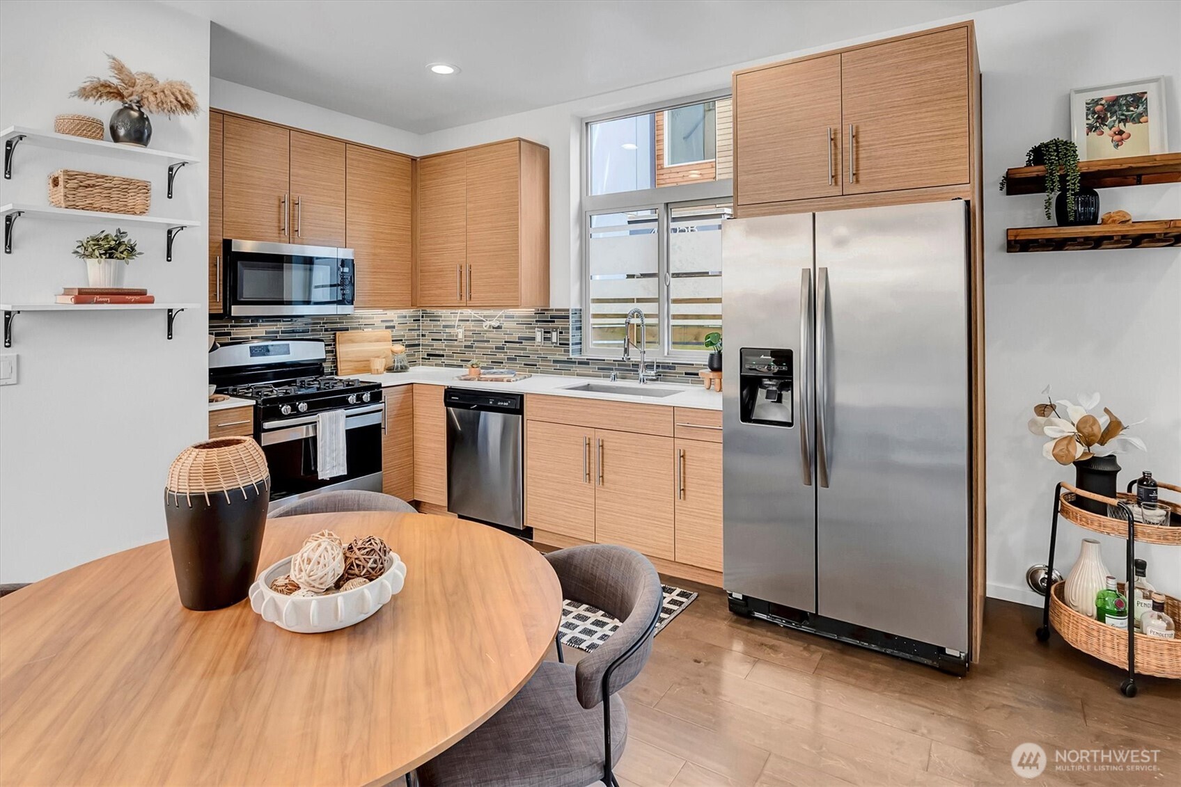 Kitchen with light wood cabinets, stainless steel appliances, and a round dining table.