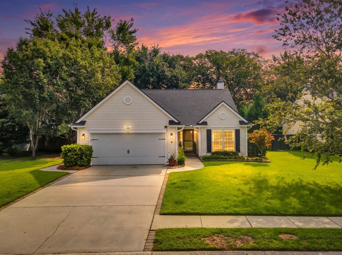 White single-story home with a two-car garage and green lawn beneath a pink sunset sky.