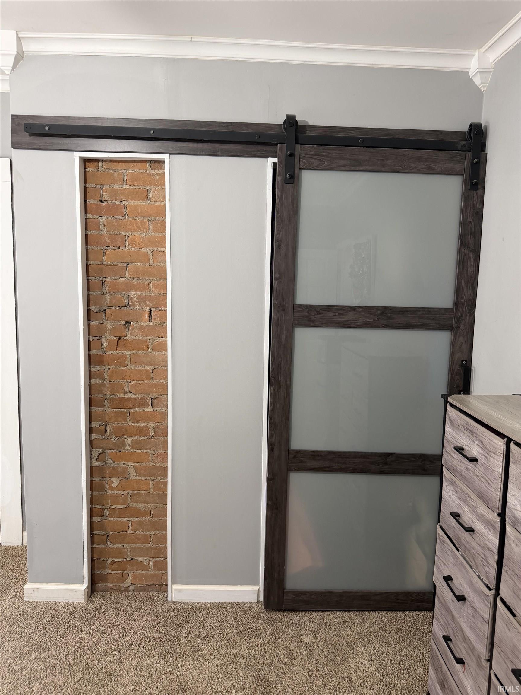 Frosted-glass barn door beside an exposed brick accent wall and wood dresser.