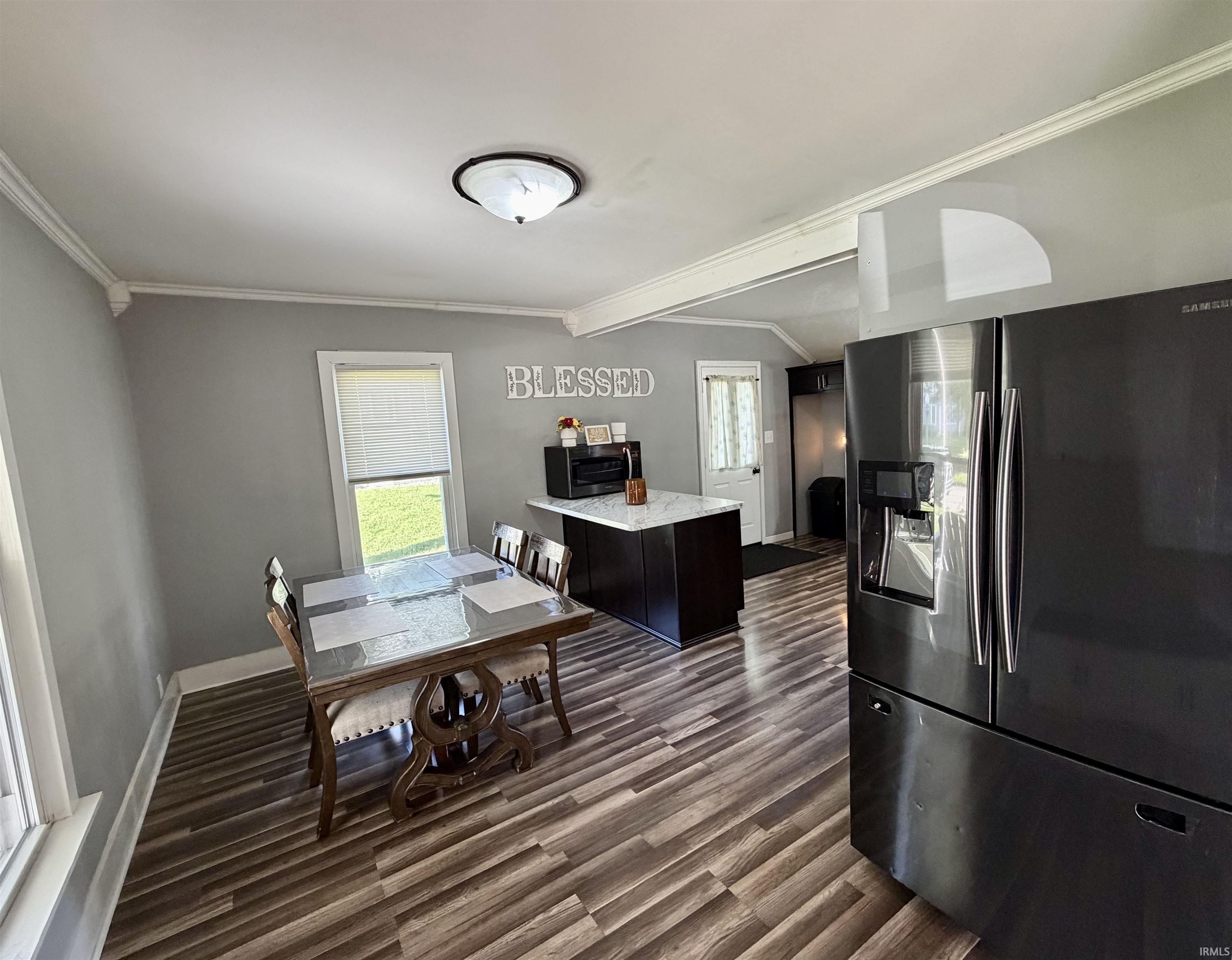 Kitchen and dining area with a marble-look island, stainless steel refrigerator, and glass-top dining table.