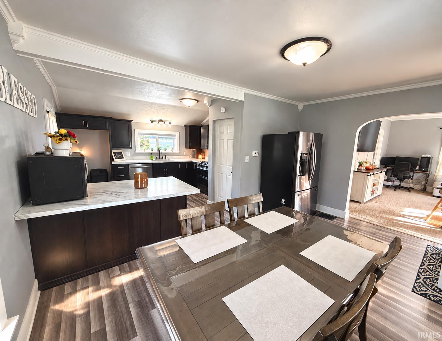 Kitchen and dining area with dark cabinets, a marble-look island, and an adjoining home office.