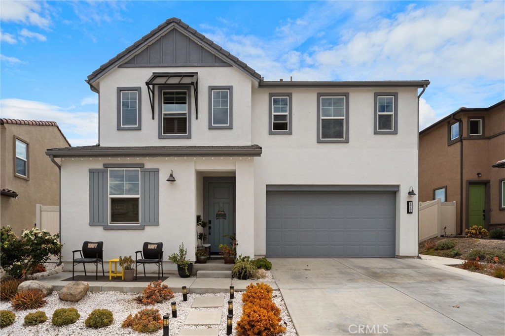 Two-story white home with gray trim, attached garage, and landscaped front yard.