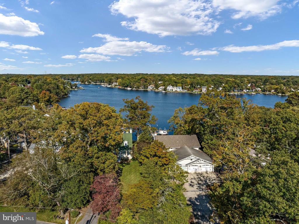 Waterfront home among autumn trees, overlooking a broad cove and wooded shoreline.