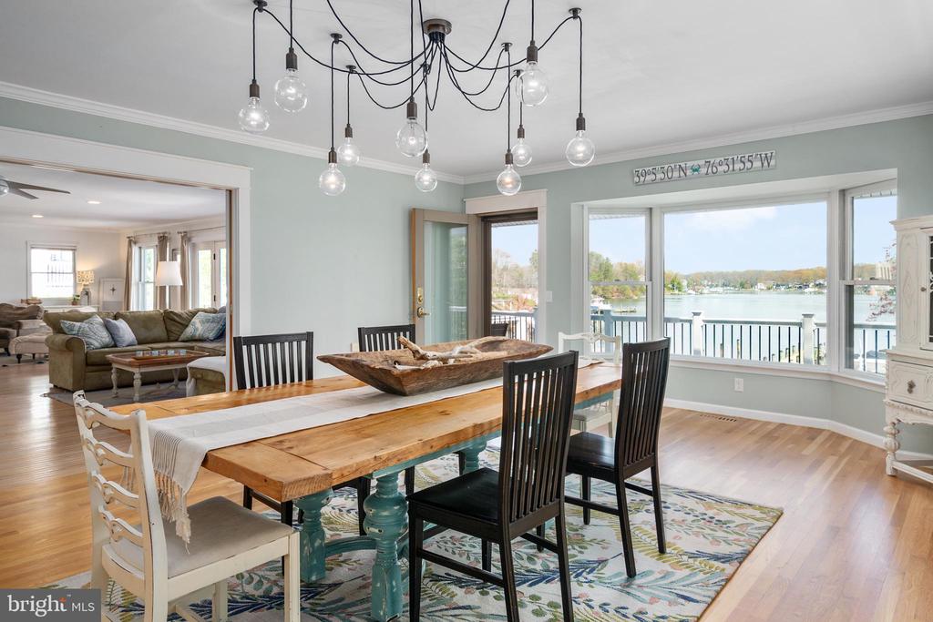 Dining room with a rustic wood table and wide windows overlooking the water.