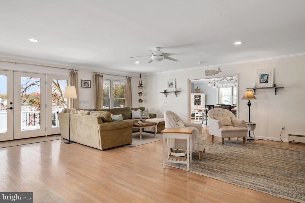 Living room with a beige sectional, hardwood floors, and French doors overlooking the water.