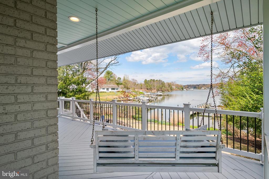Covered waterfront deck with a hanging white swing and views across the water.