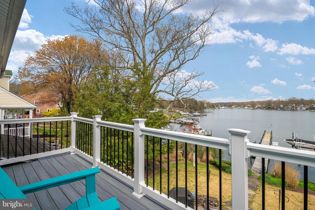 Waterfront deck with turquoise chairs overlooking a calm bay and shoreline docks.