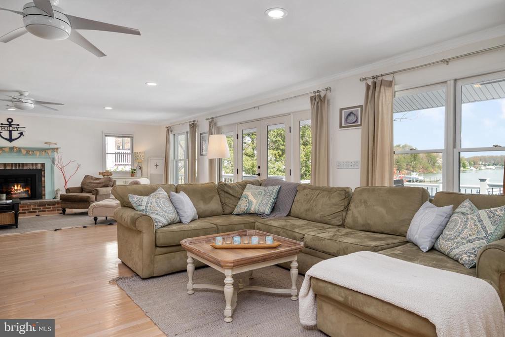 Living room with a large sectional sofa, fireplace, and windows overlooking the water.