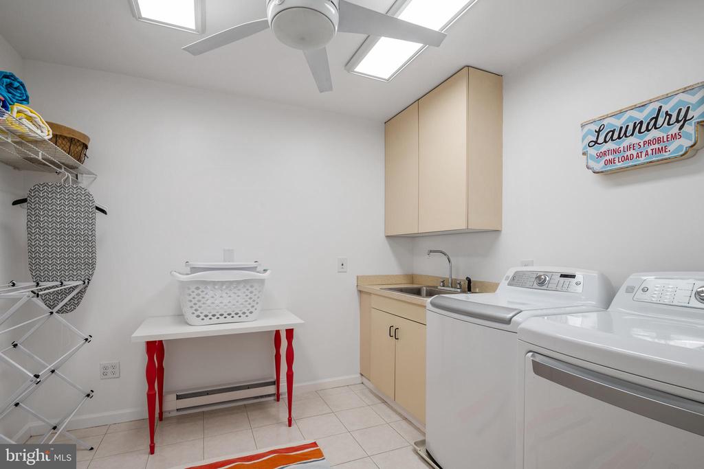 Laundry room with washer and dryer, utility sink, skylights, and a folding table.