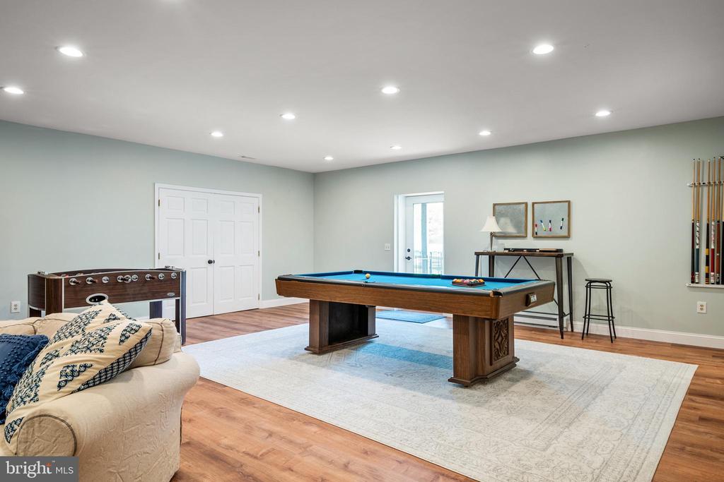 Recreation room with a pool table, foosball table, and cream sofa.