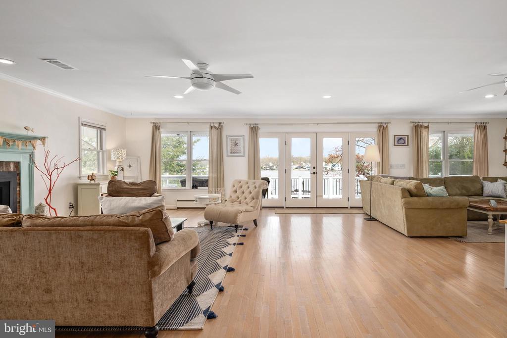 Furnished living room with hardwood floors and glass doors overlooking the water.