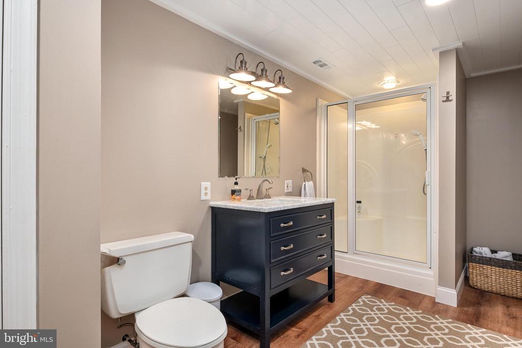 Bathroom with a dark blue vanity, glass-enclosed shower, and patterned rug.