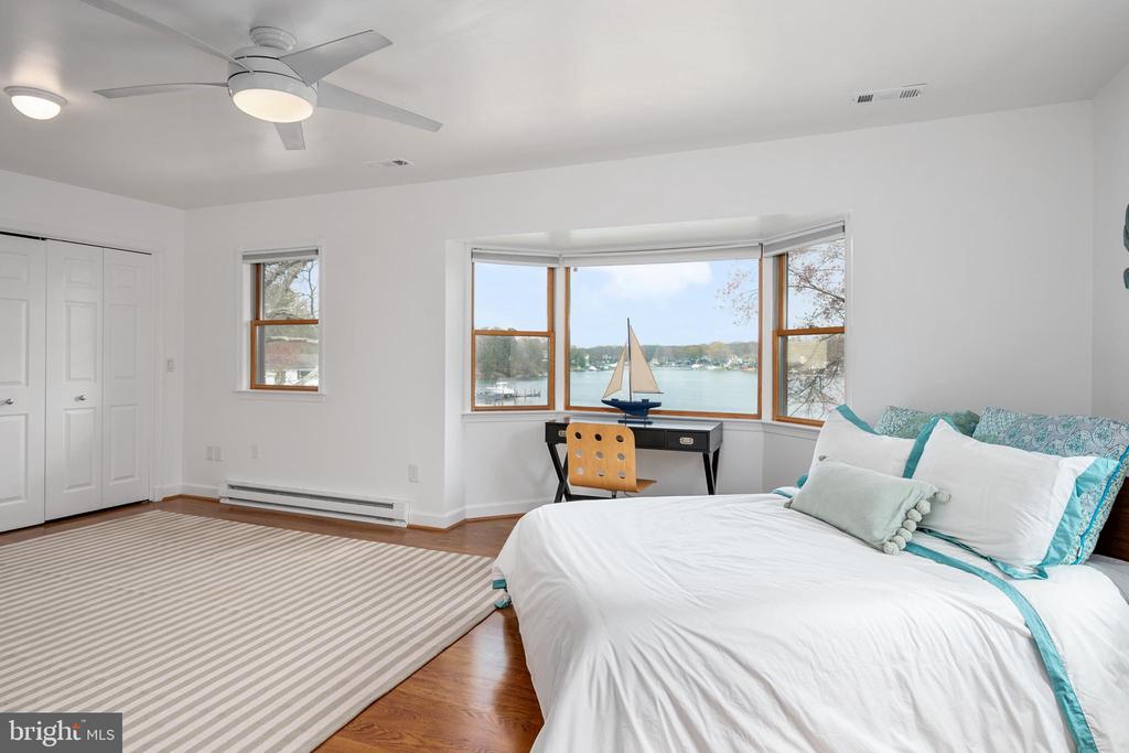 Bedroom with a white bed and bay window overlooking the water.