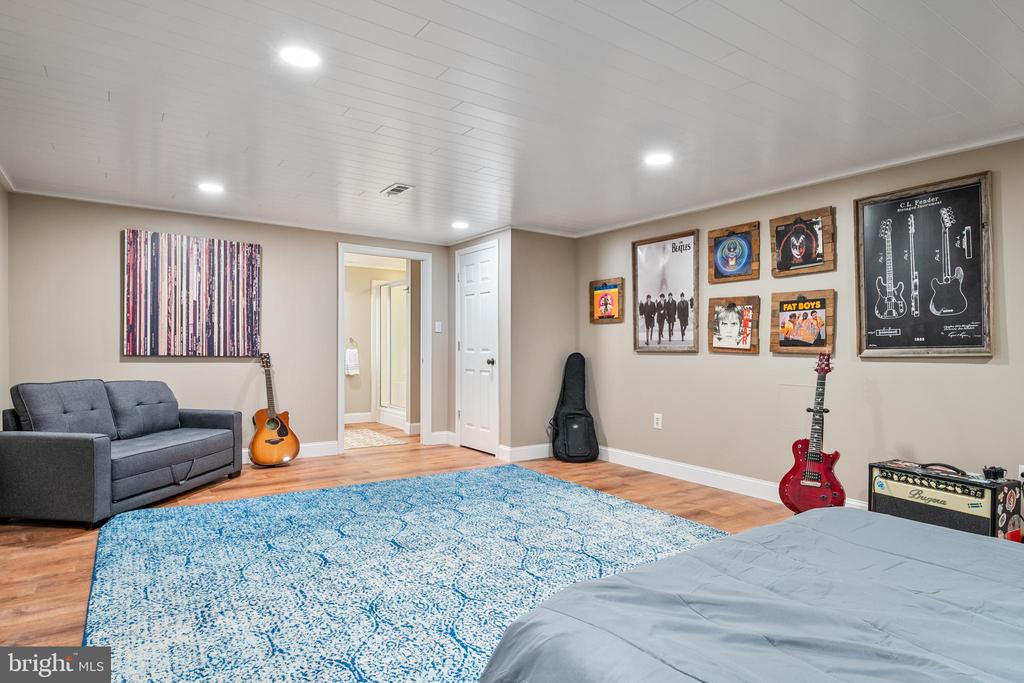 Bedroom with a blue patterned rug, guitars, and music-themed wall art.