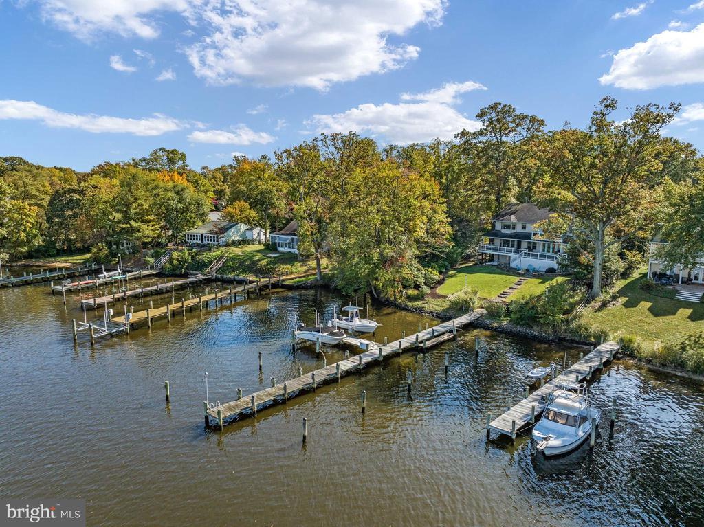 Aerial view of waterfront homes with private docks and boats along a wooded shoreline.