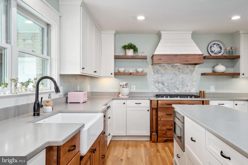 Kitchen with a farmhouse sink, white cabinets, wood accents, and a large island.