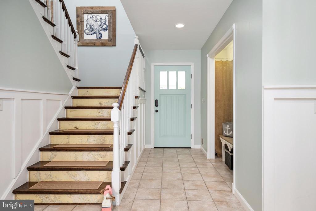 Entry foyer with a pale blue front door and staircase with map-patterned risers.