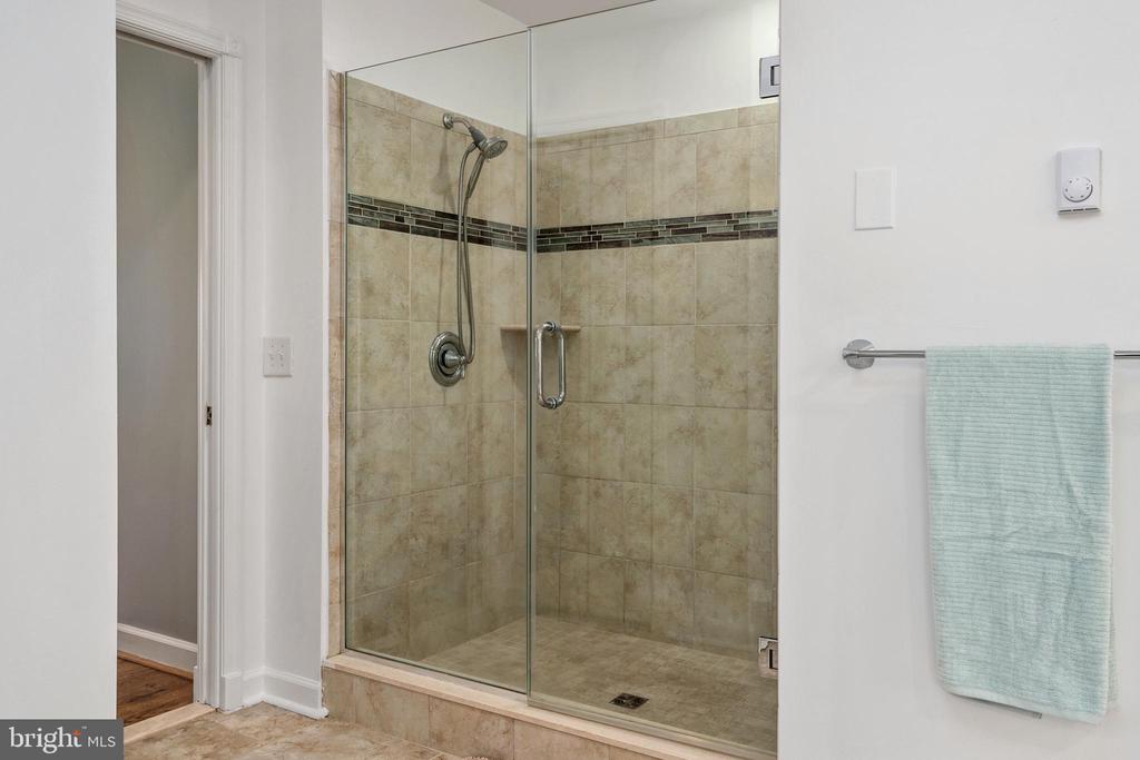 Bathroom with a glass-enclosed tiled shower and pale aqua towel.