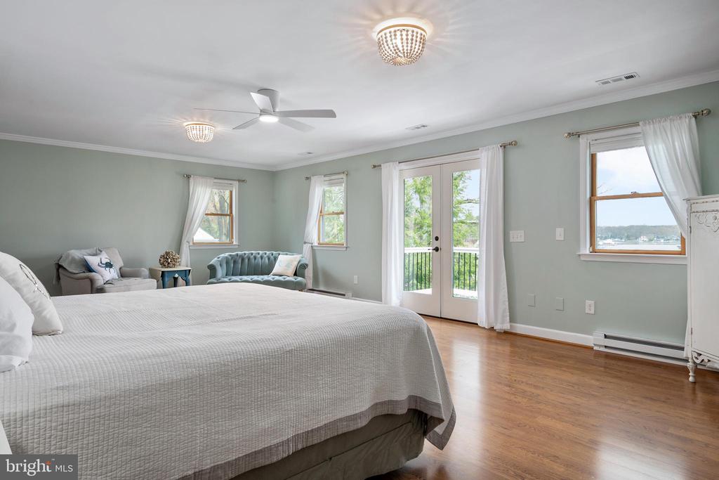 Furnished bedroom with French doors, hardwood floors, and a water view through the windows.