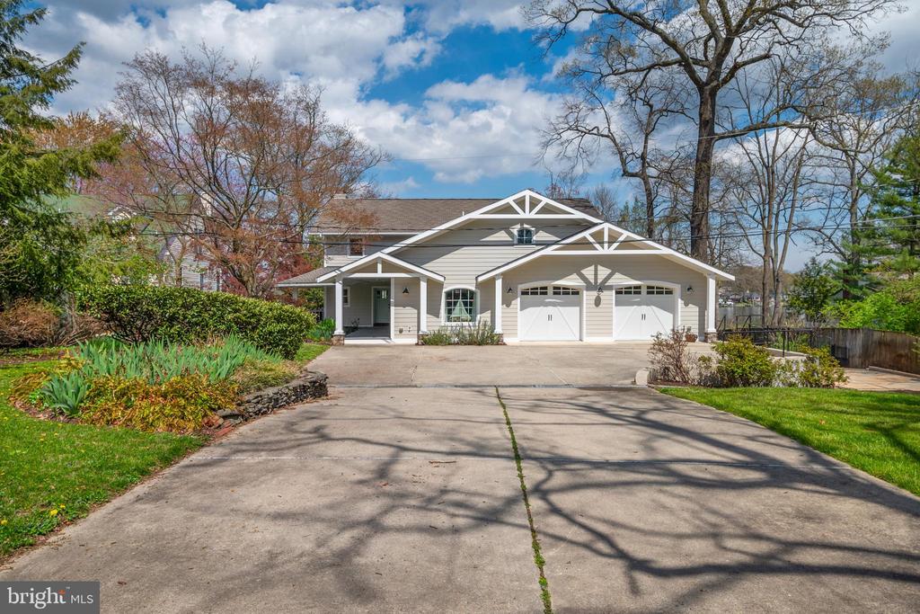 Light-colored home with two garage doors and a wide driveway framed by spring landscaping.