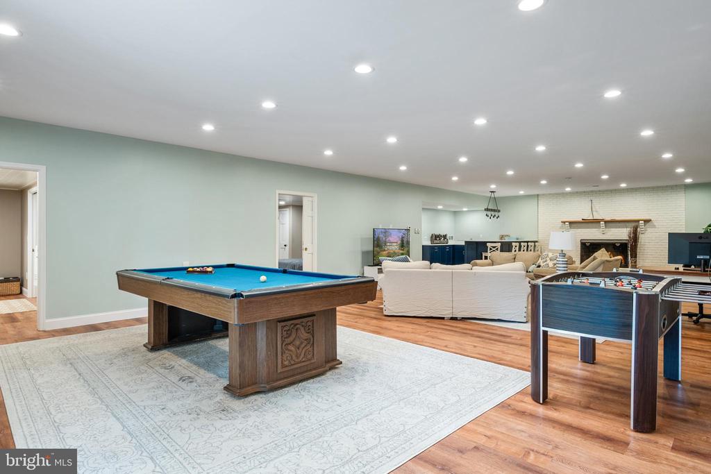 Furnished recreation room with a pool table, foosball table, sectional seating, and brick fireplace.