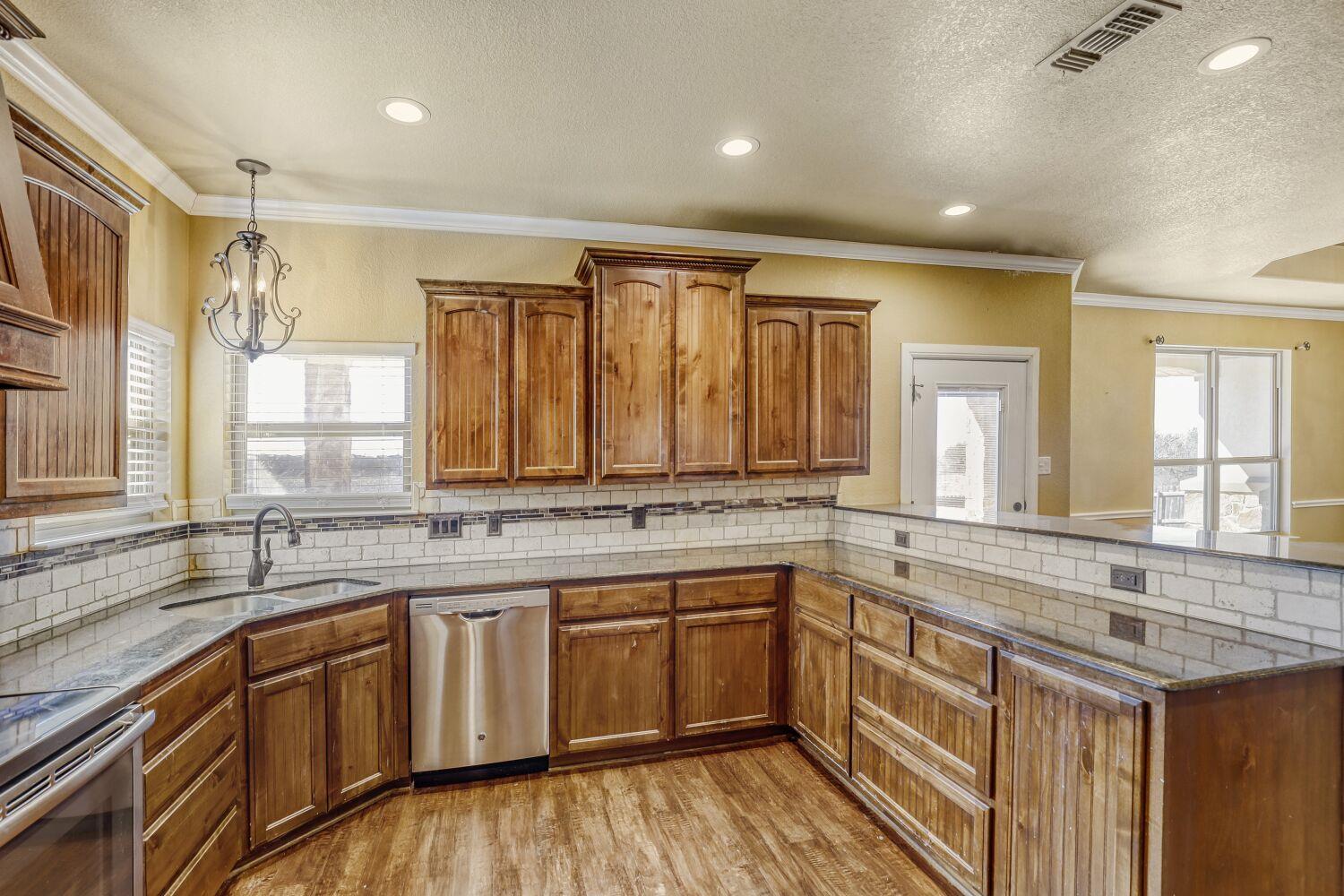Kitchen with warm wood cabinets, light counters, subway-tile backsplash, and stainless steel appliances.