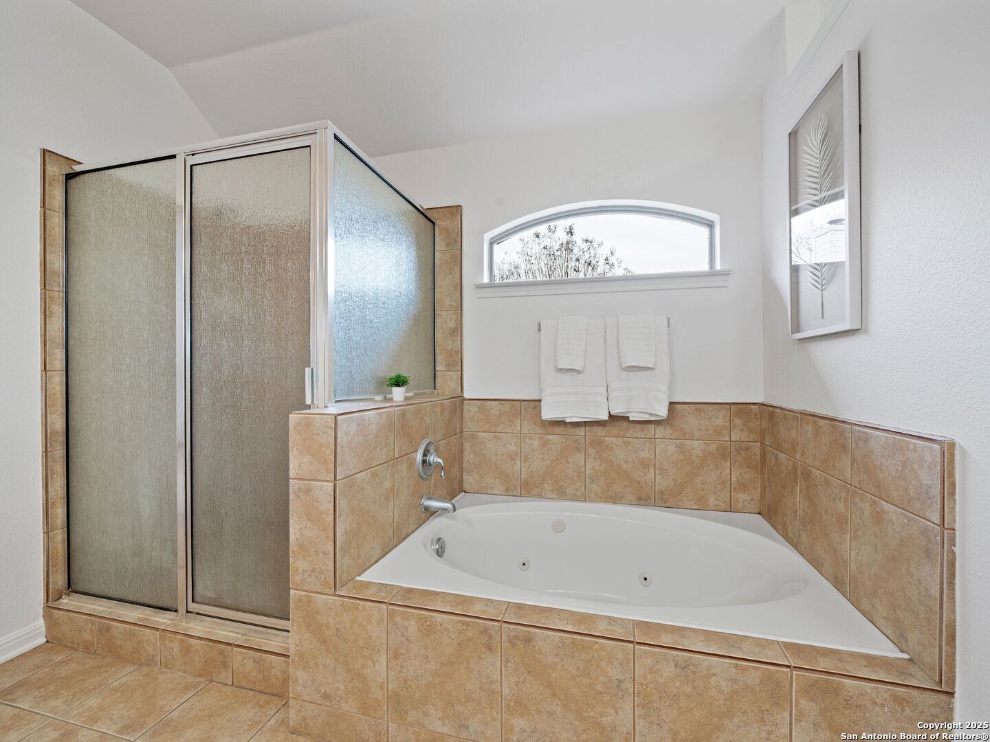 Bathroom with a built-in jetted tub, tan tile, and a separate frosted-glass shower.