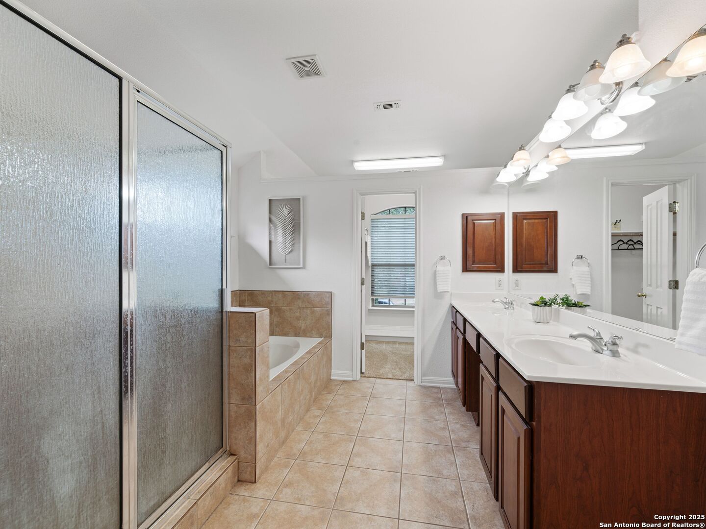 Spacious bathroom with a frosted-glass shower, corner soaking tub, and dark wood double vanity.