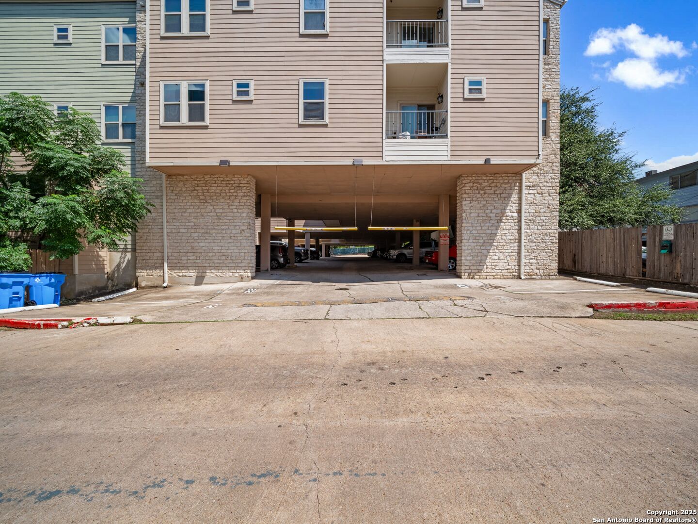 Apartment building exterior with a covered parking entrance and balconies above.