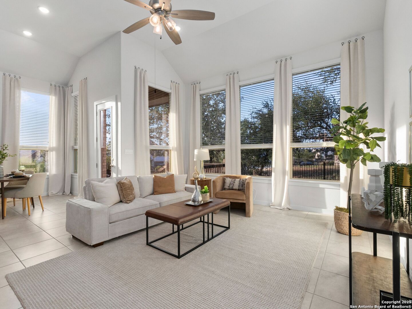 Living room with vaulted ceiling, gray sectional sofa, and large curtained windows.
