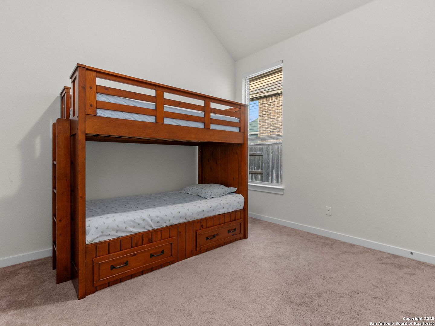 Bedroom with a dark wood bunk bed featuring built-in drawers and a lower bed.