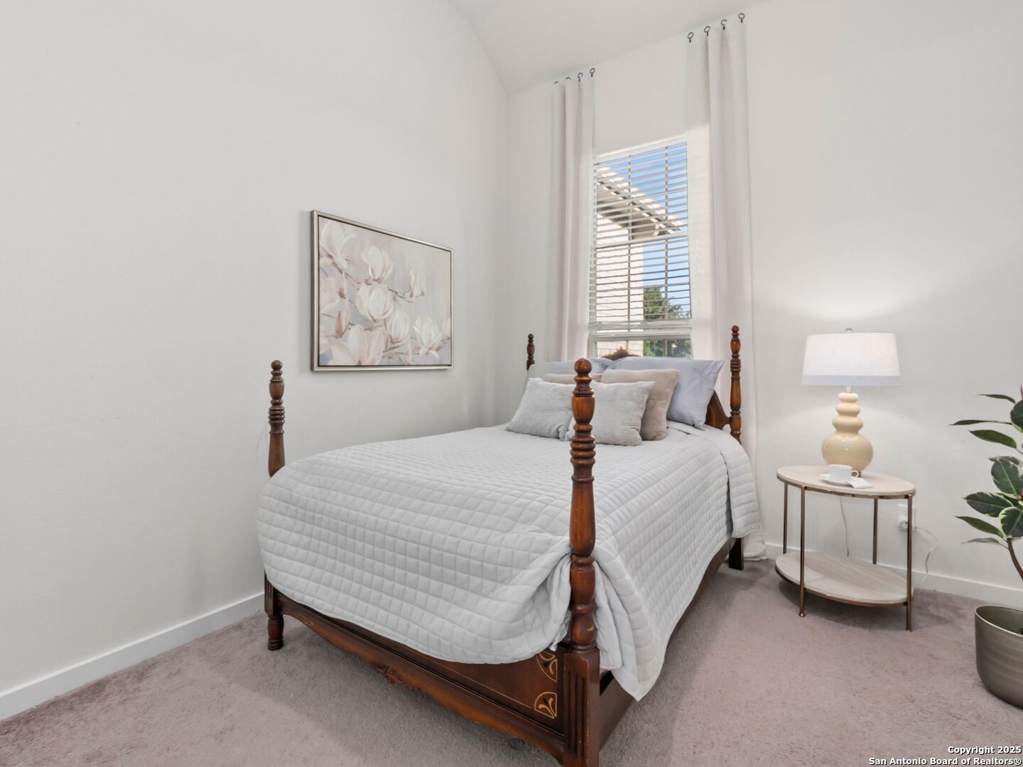 Staged bedroom with a dark wood four-poster bed, white bedding, and a tall curtained window.